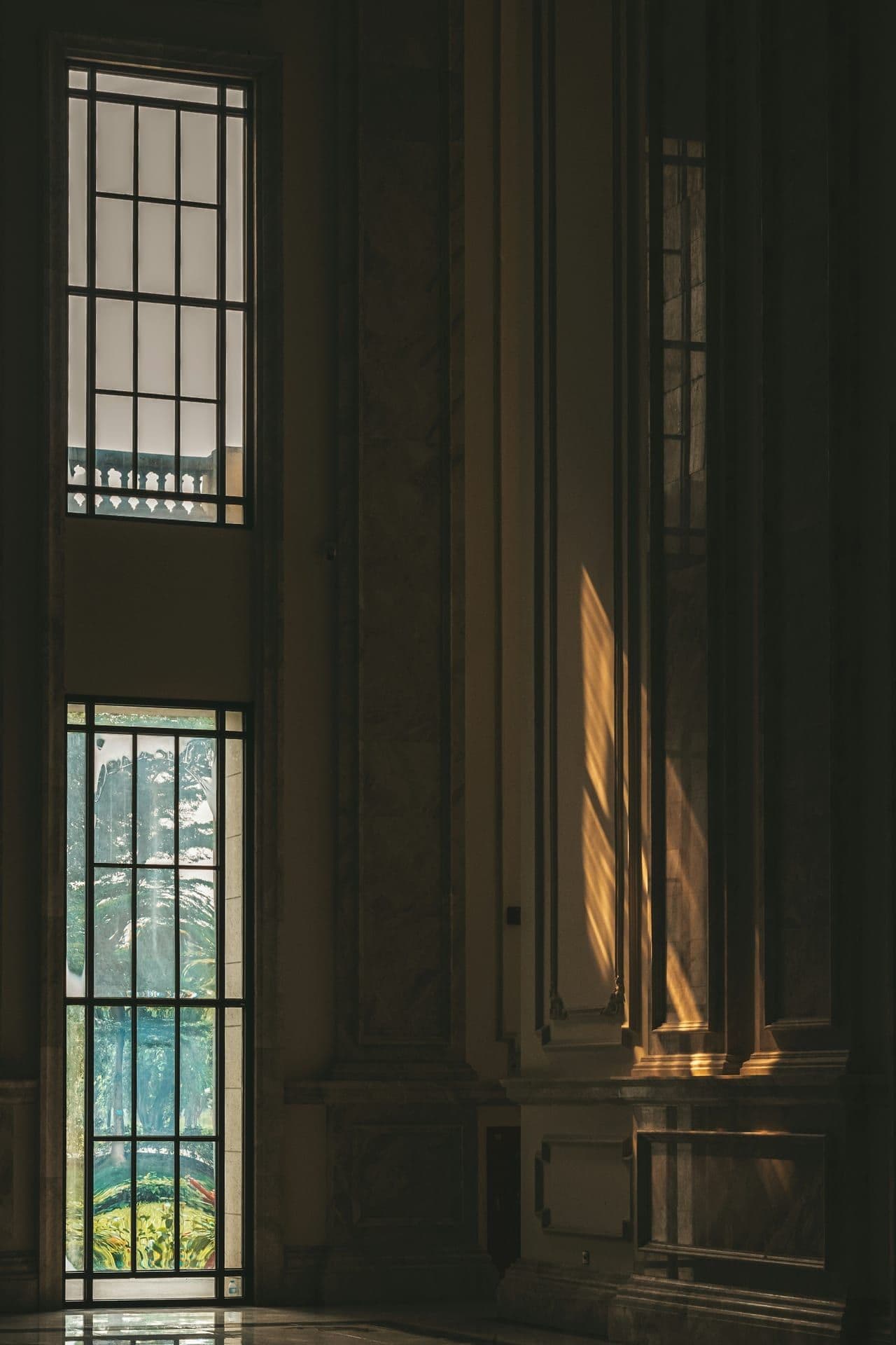 Late light raking across the stone paneling of a courthouse hall