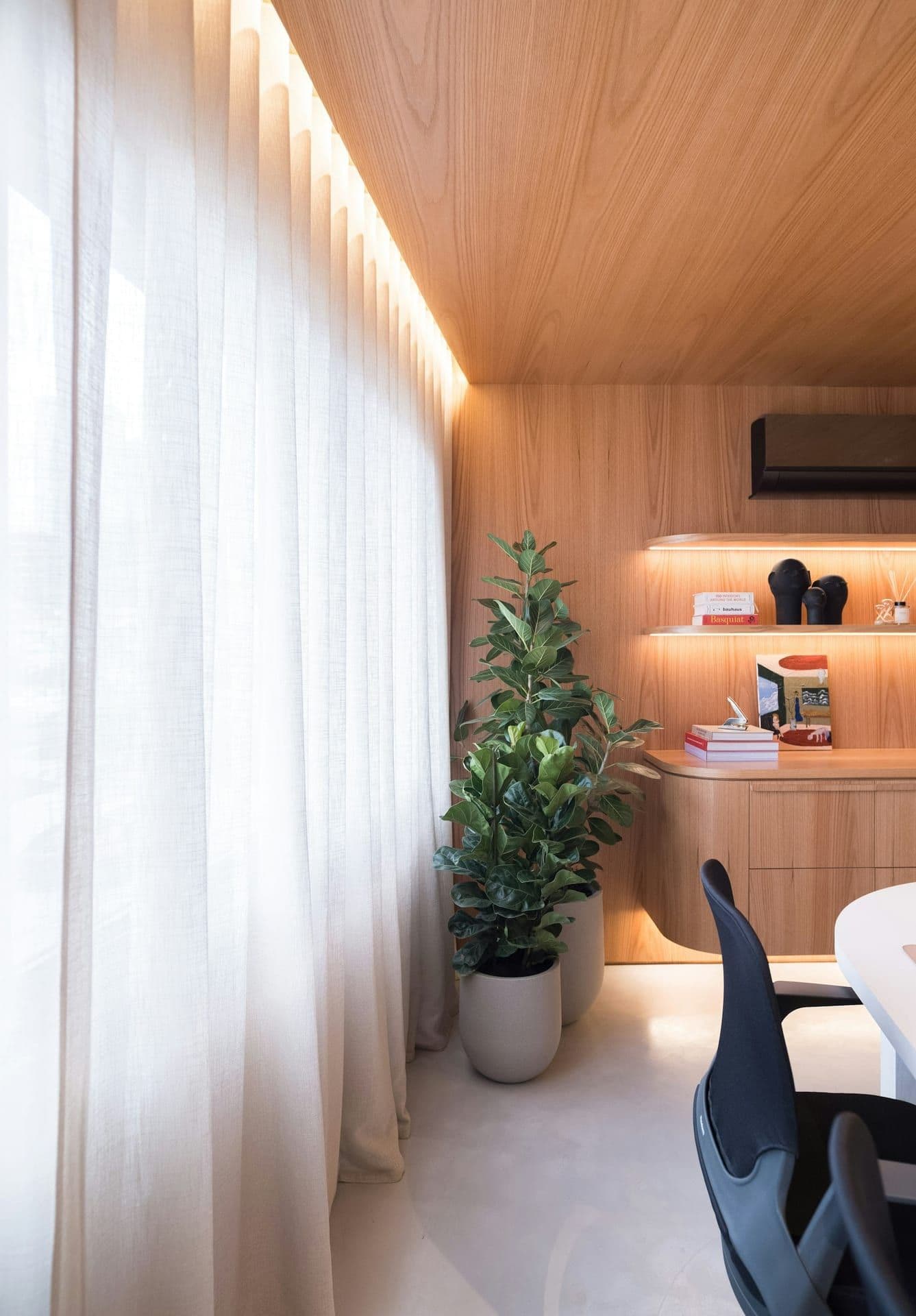 A warm, wood-lined meeting room at the firm, low evening light falling through sheer curtains