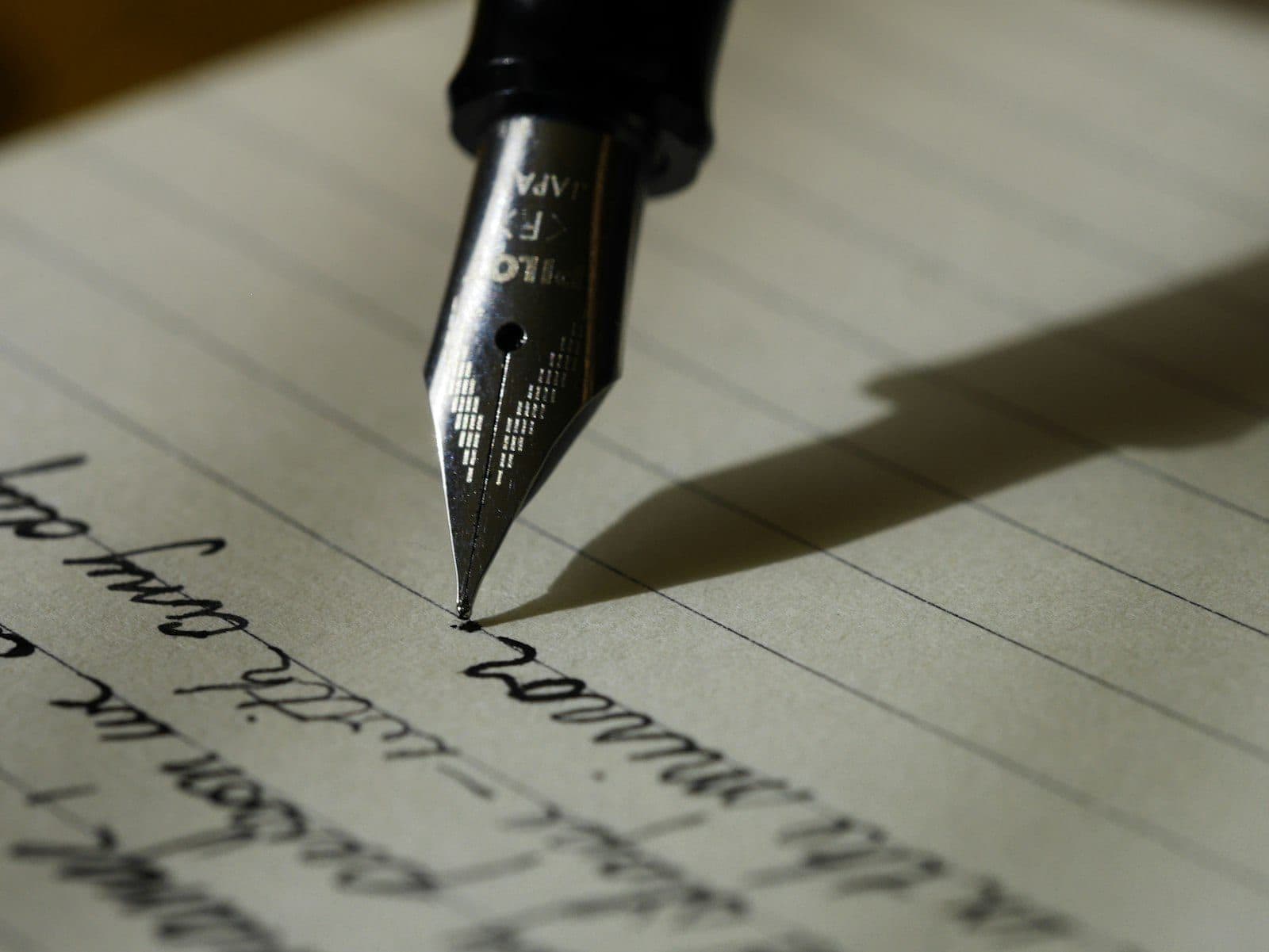 A fountain pen resting on lined archival paper, mid-signature